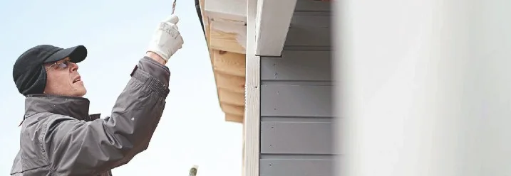 Person streicht Hauswand mit Pinsel